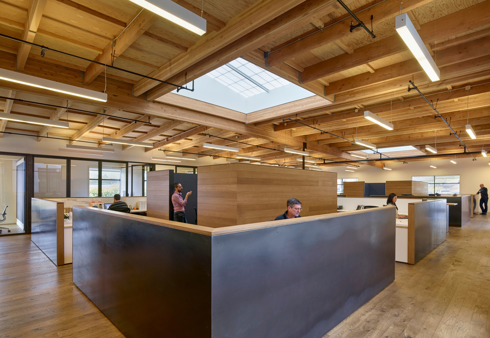 A large skylight above an open office floor plan helps everyone enjoy the benefits of natural light, even for occupants sitting towards the center of the space away from exterior windows