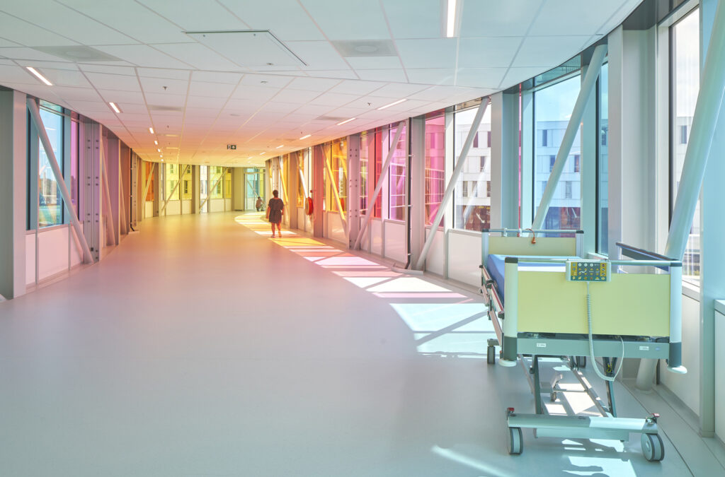Recessed lighting with color tuning down this hospital hallway creates a color spectrum effect as people walk down the hall