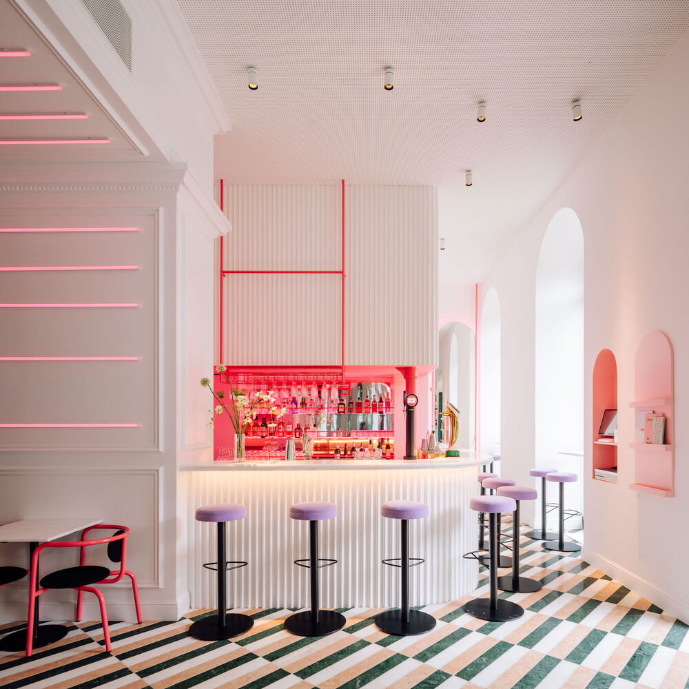 This modern restaurant and bar space uses magenta and other hues of pink with pink accent lighting and warm color-tunable lighting to create a fun atmosphere 