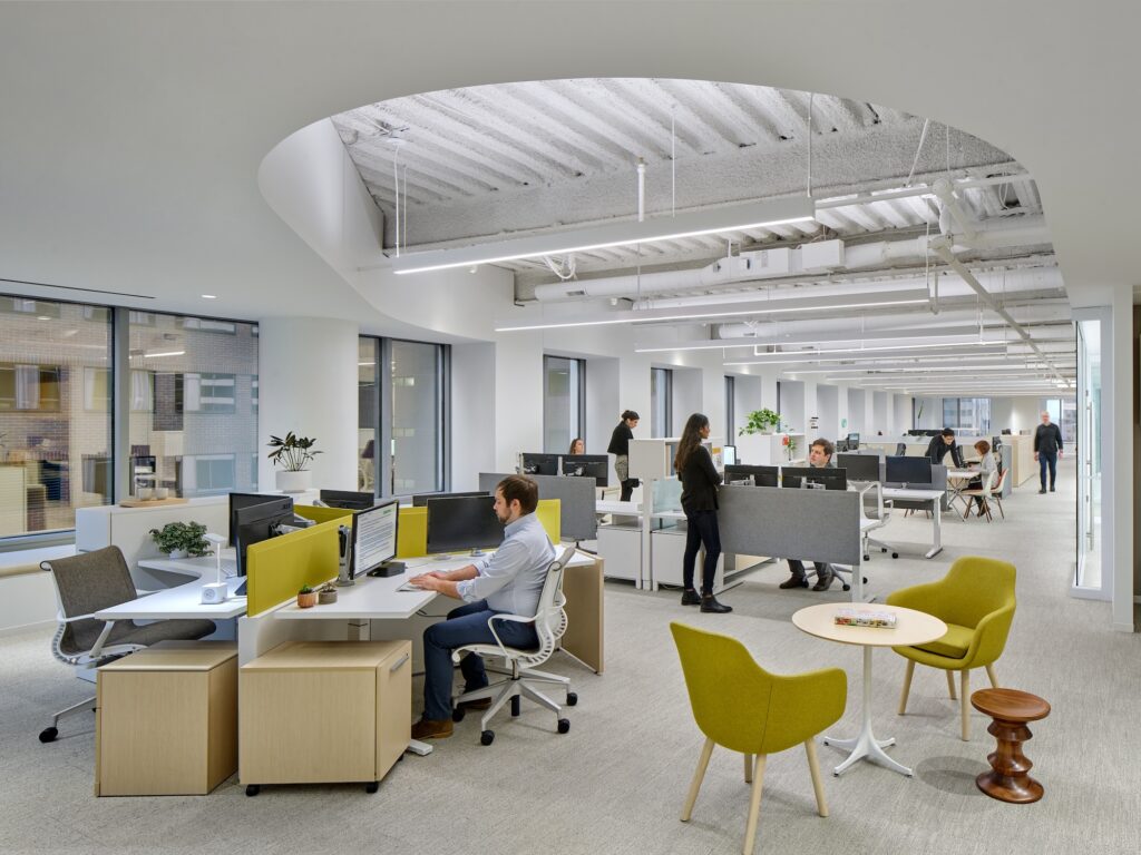 A modern office with curved skylight cutouts and color-tunable LED lighting.
