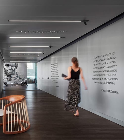 Linear recessed lights provide general lighting down a corridor with monopoint spotlights highlighting memorabilia along the wall at the Chicago Tribune offices.