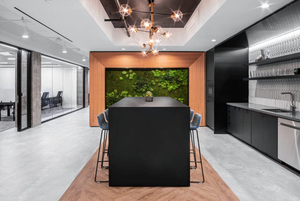 Wood flooring and wall panels as well as a green wall bring nature indoors in the kitchenette of a modern office space