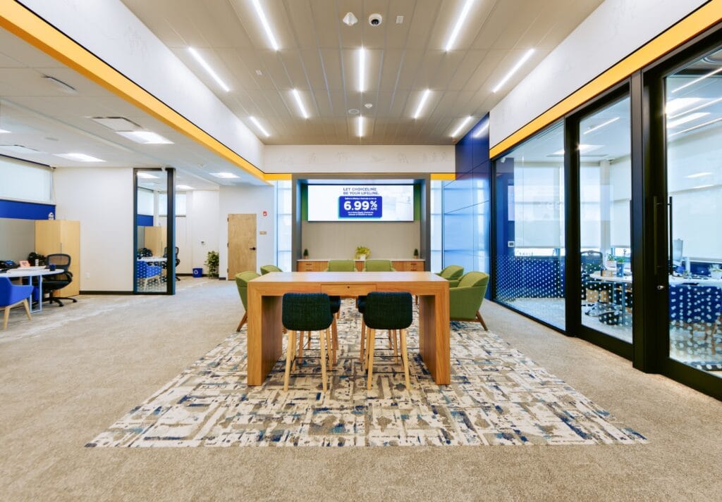 Linear recessed lights fit in a ceiling grid system over a meeting space.
