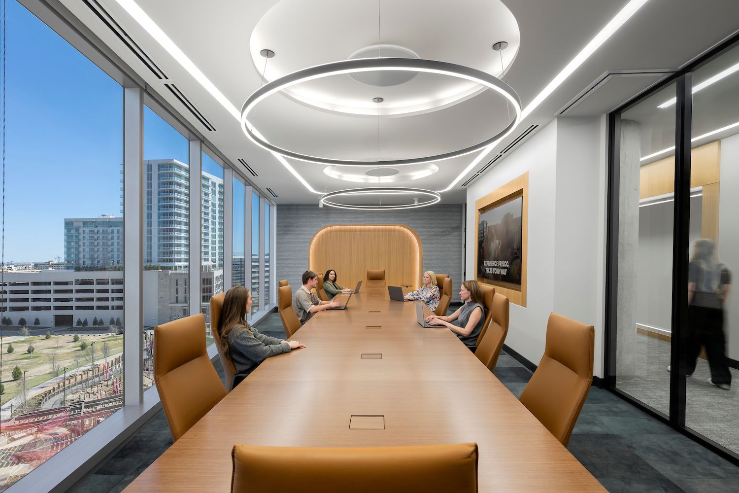 An office conference room lit with two simple but elegant single-tier LED ring pendant lights.