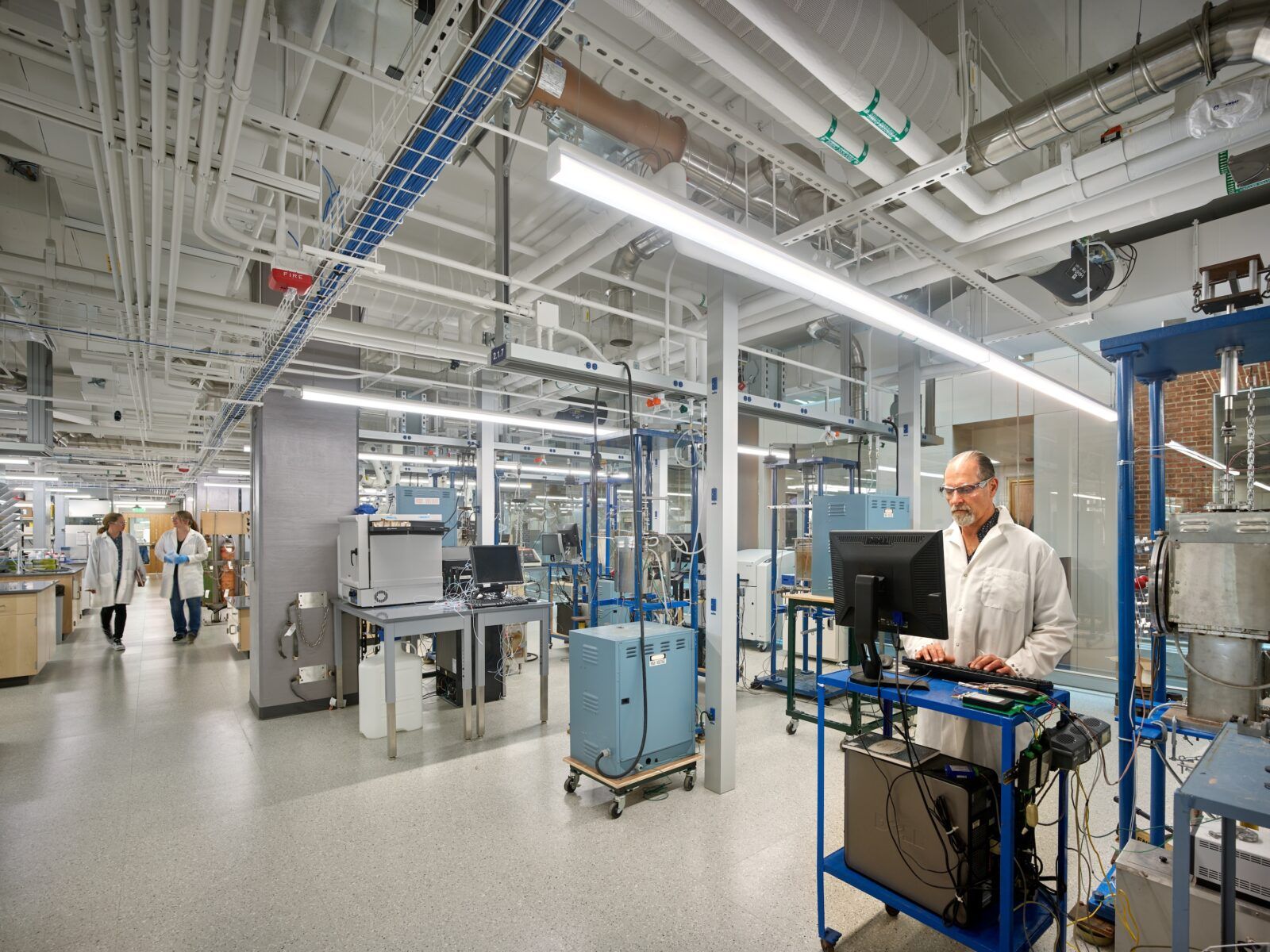 A closed medical lab, lit by linear pendants, also features clear emergency lighting in case of outages.
