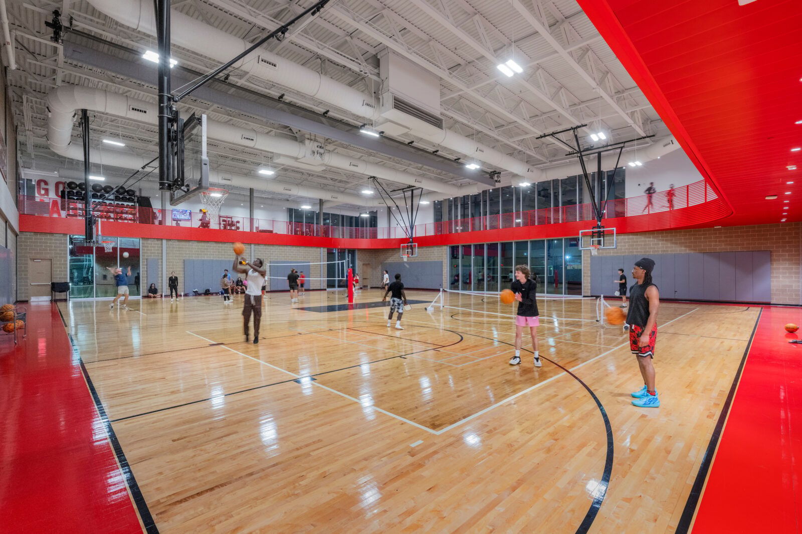 Suspended linear LED lights illuminate a large indoor gymnasium at Texas A&M University.
