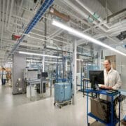 A closed medical lab, lit by linear pendants, also features clear emergency lighting in case of outages.