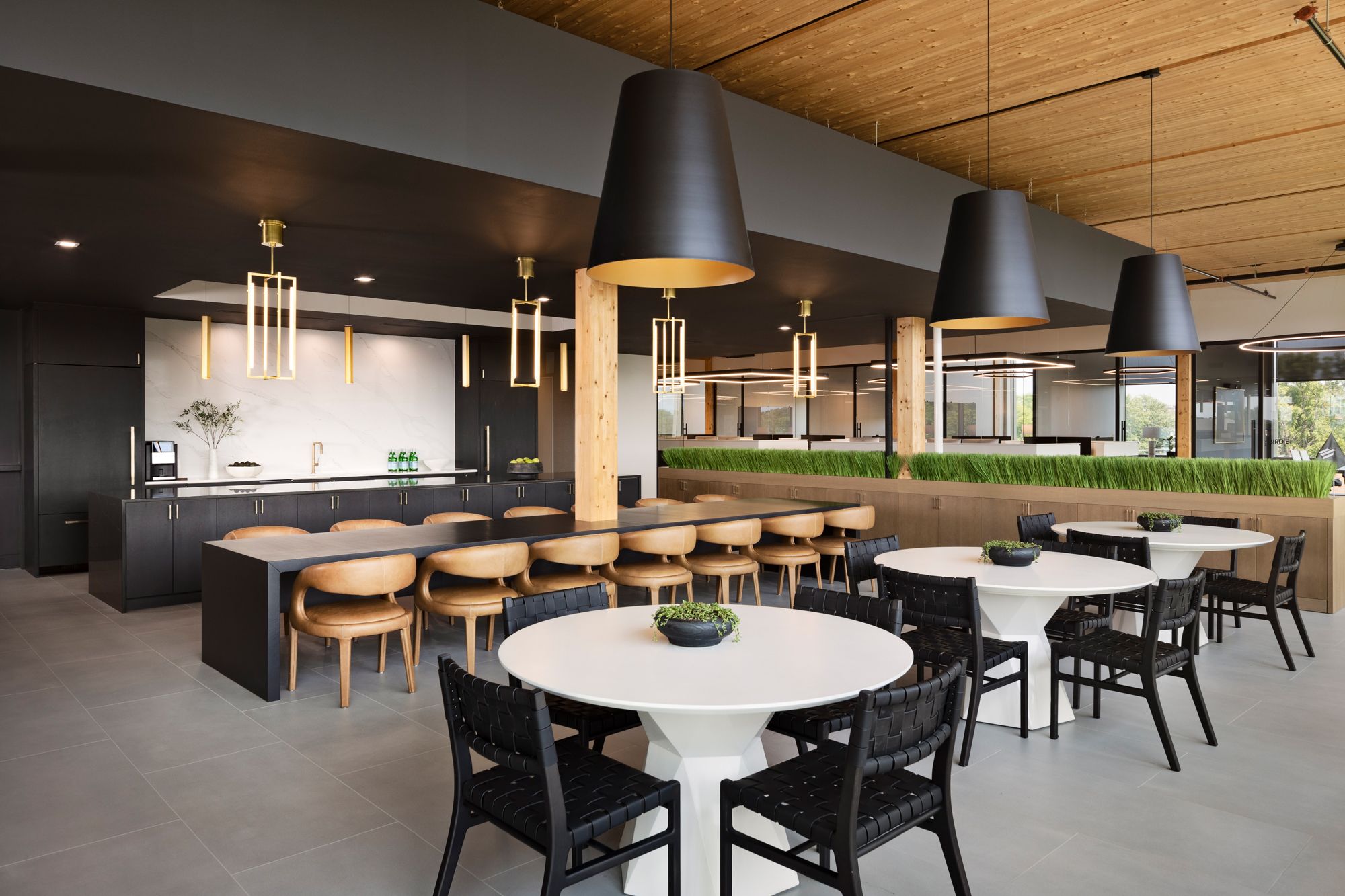 Stylish decorative pendants provide warm lighting over tables in a restraurant-style employee lounge.
