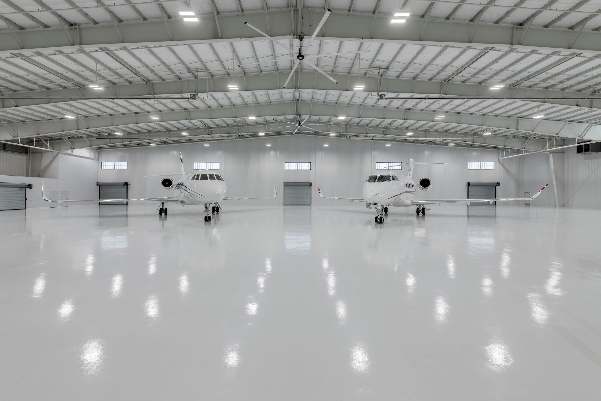 Pendant-mounted LED high bay lights illuminate aircraft and maintenance areas inside a large commercial hangar.