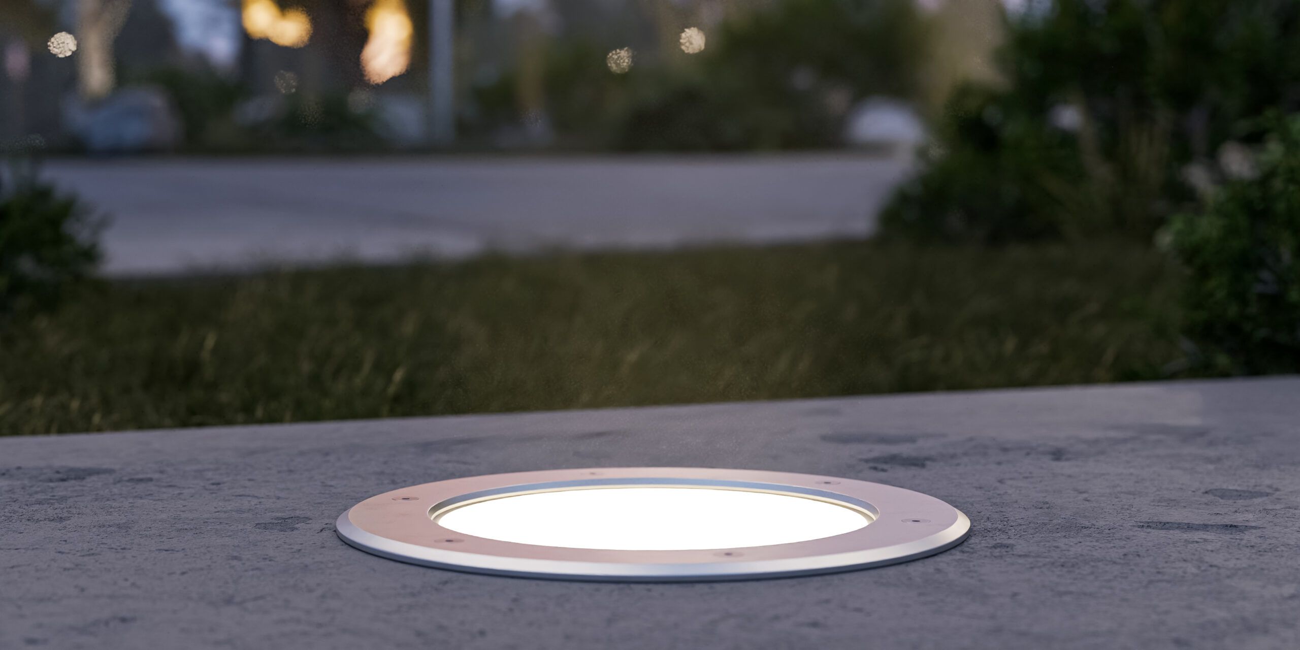 Alcon 9094 LED in-ground uplight installed flush in concrete surface with illuminated lens.