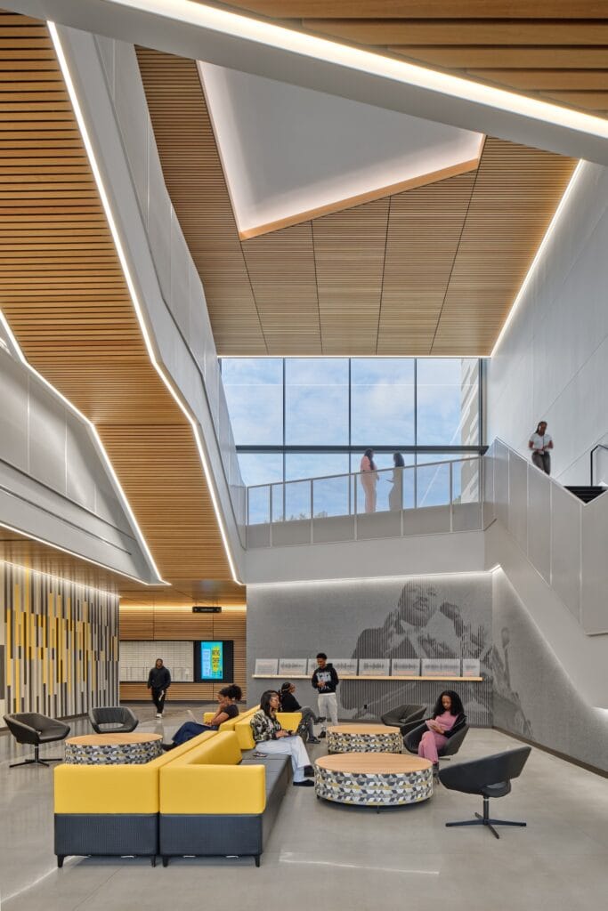 Integrated linear LED lighting supplements natural light entering a modern commercial interior through expansive glazing and overhead openings.
