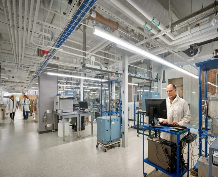 A closed medical lab, lit by linear pendants, also features clear emergency lighting in case of outages.