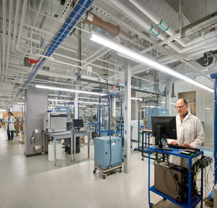 A closed medical lab, lit by linear pendants, also features clear emergency lighting in case of outages.