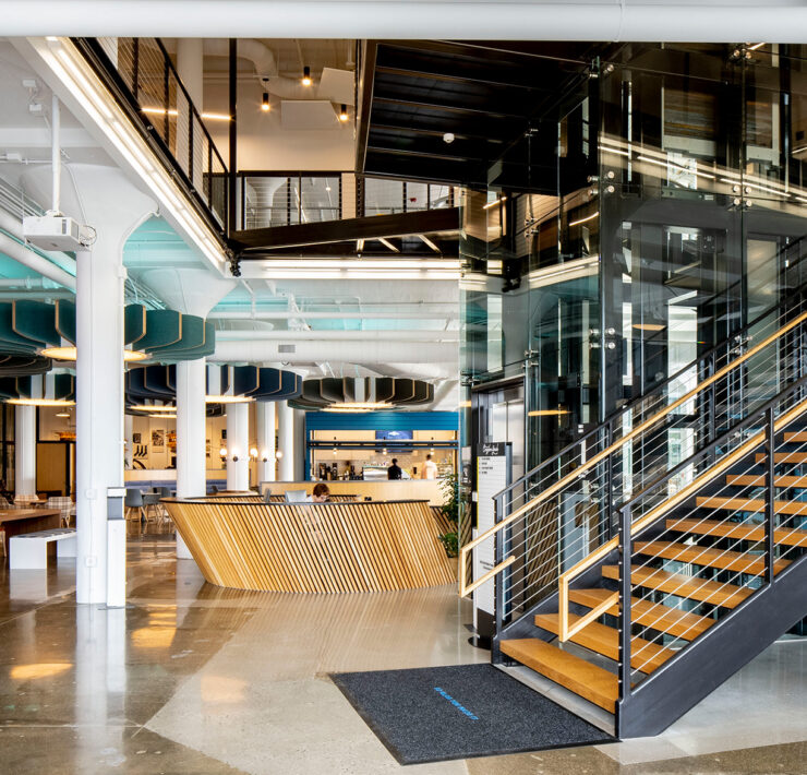 You can find several architectural trends for 2023 featured in the Plant Seven coworking space in Highpoint, North Carolina, including rounded pendants, bold pops of color, natural wood finishes, and homey plaid-patterned chairs