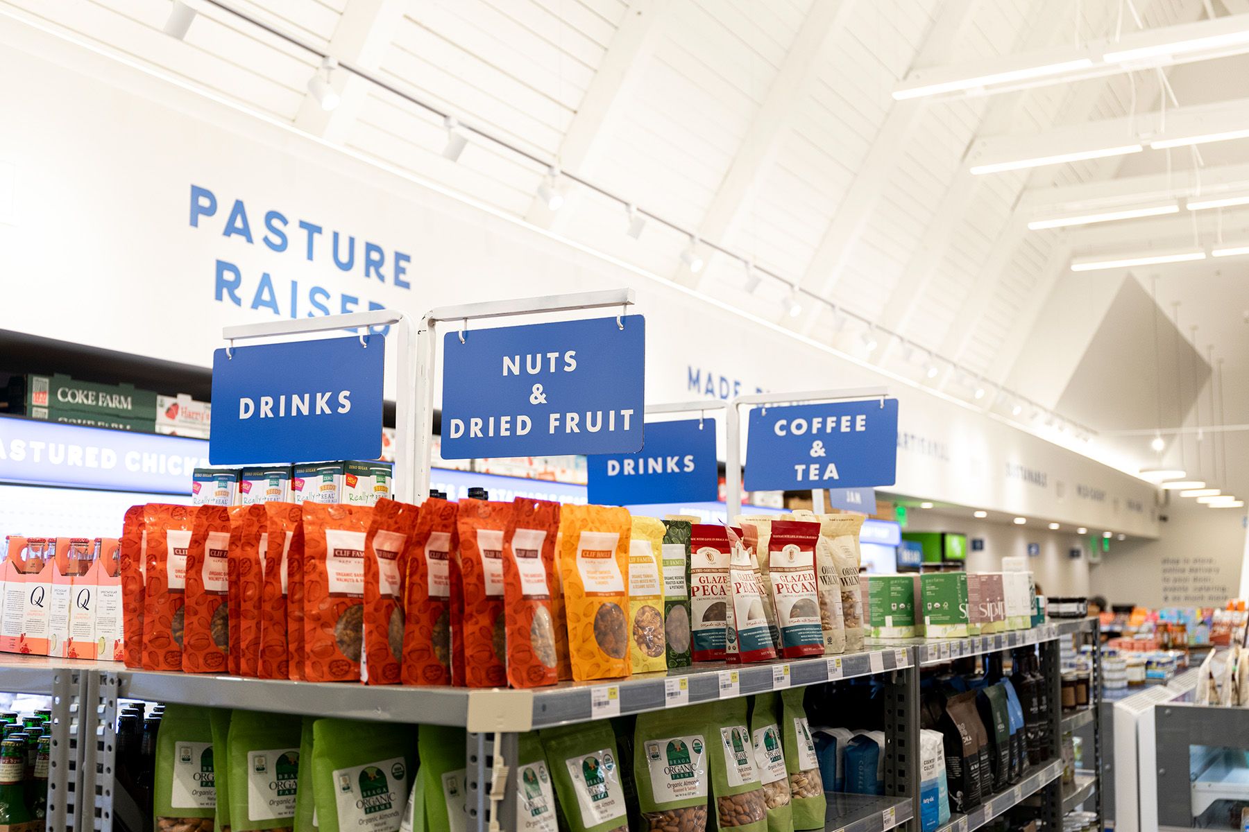 White LED track lights illuminate signage and product displays in an organic grocery store.