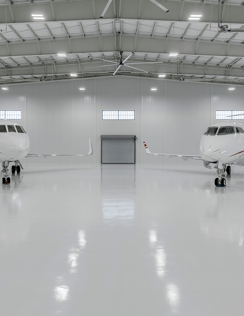 LED high bay lighting provides broad illumination across an aircraft hangar with high ceilings, open floor area and parked planes.