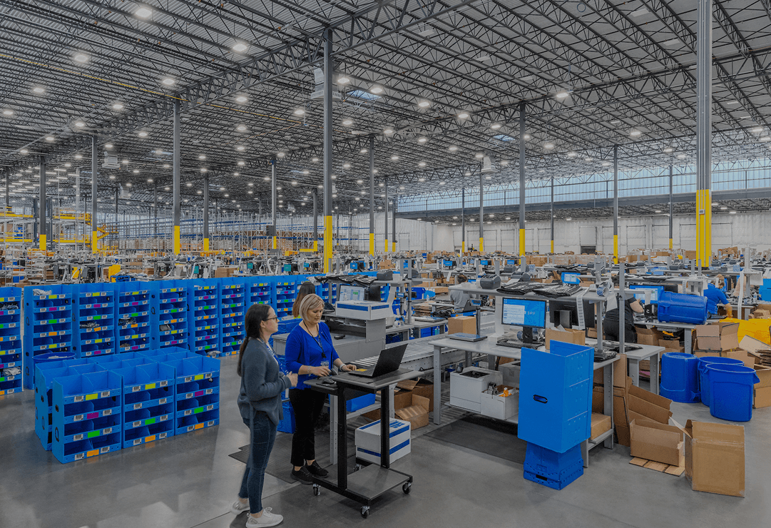 LED high bay lighting provides broad illumination across a warehouse distribution center with high ceilings and active fulfillment operations.