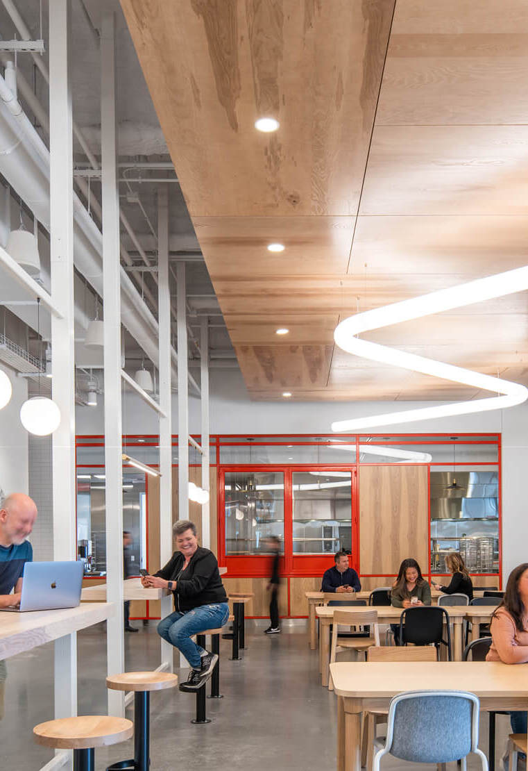 Corporate break area with modern LED pendant lighting, including globe pendants and a continuous run of suspended linear light.