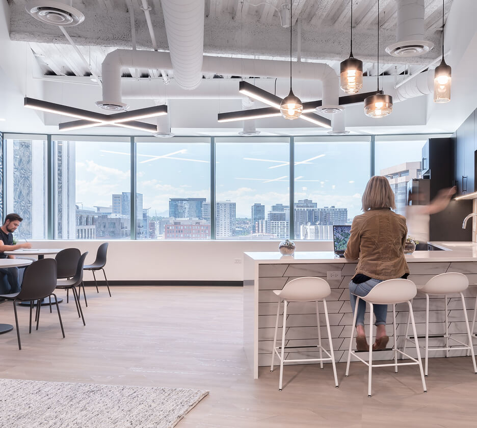 Modern X-shaped LED pendant lights offer low-glare accent lighting in a WeWork kitchen breakroom.