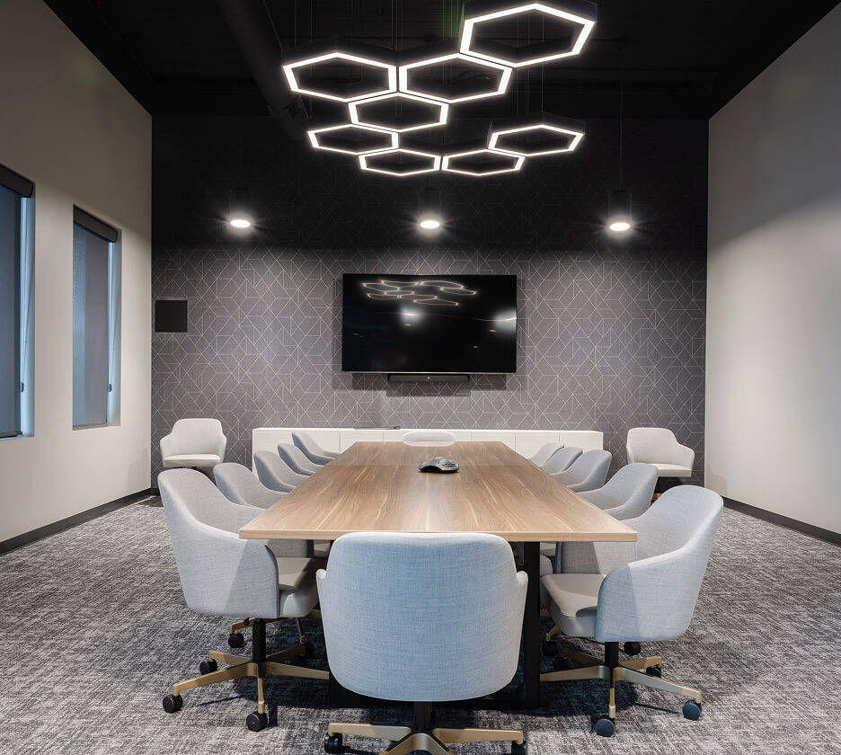 Hexagon pendant lights set in a honeycomb pattern create a modern lighting aesthetic over a conference room table.