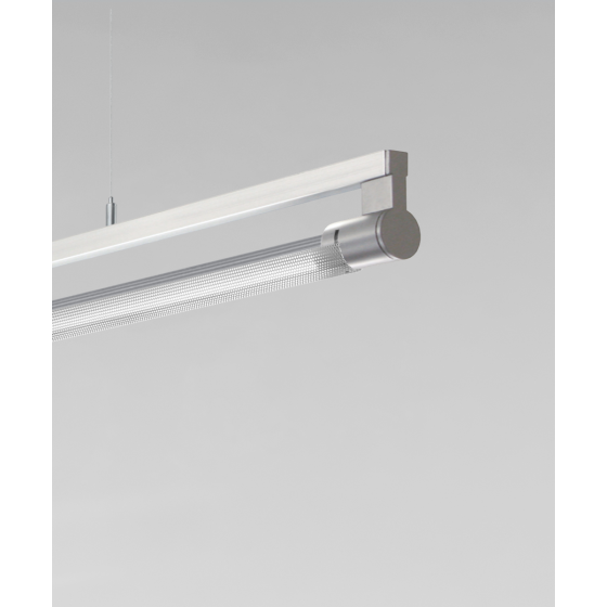 Alcon 12160-P-PD, suspended linear pendant light shown in silver finish, with a rotating cylindrical half-lite lens, and a curved perforated lens cap.
