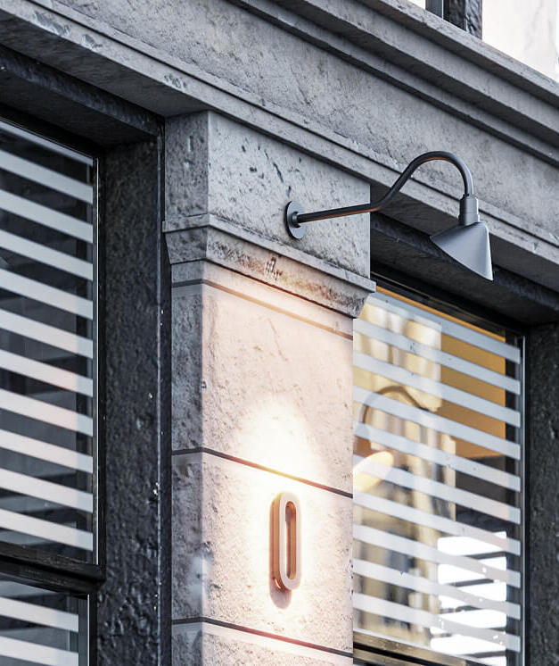 Gooseneck LED sign lights illuminate building numbers along an exposed commercial facade.