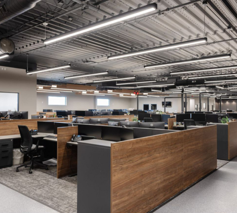 Direct/indirect linear pendant lights reduce glare over office workstations while highlighting an industrial ceiling.