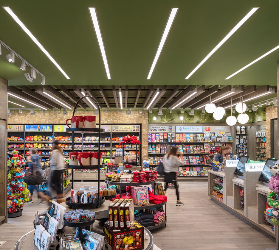 Flanged recessed linear lights provide ambient lighting in an airport retail convenience store.