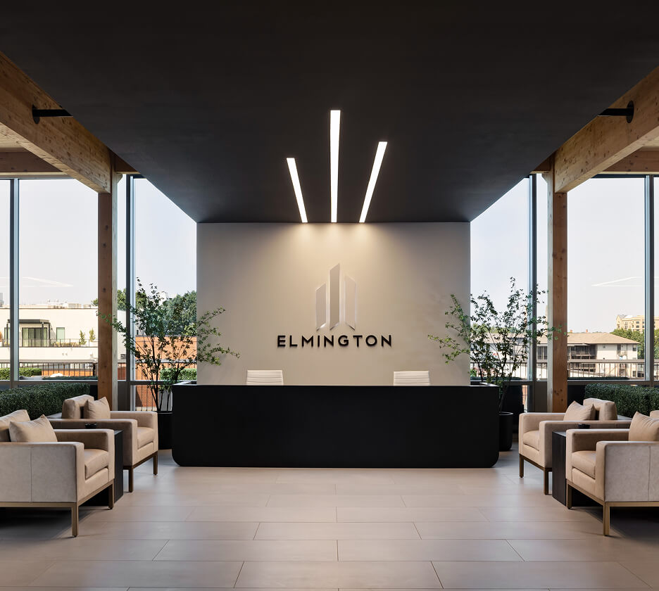 Three custom-length linear recessed lights recreate the Elmington logo on the ceiling over the welcome desk.