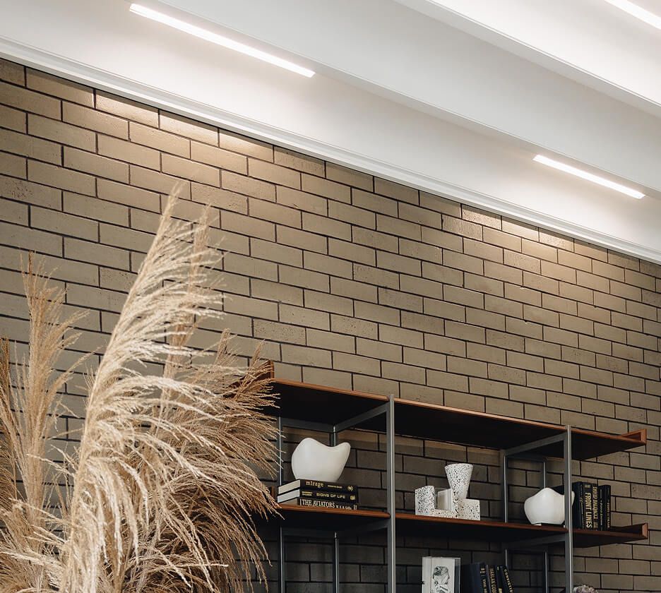 Linear recessed lights fit in a white wood ceiling provide ambient lighting in a podcast studio office.