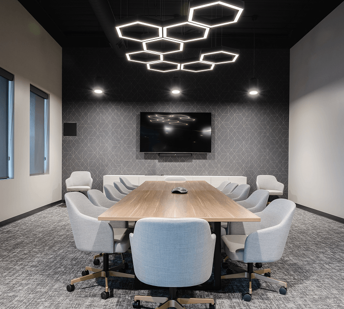 Hexagon pendant lights set in a honeycomb pattern create a modern lighting aesthetic over a conference room table.