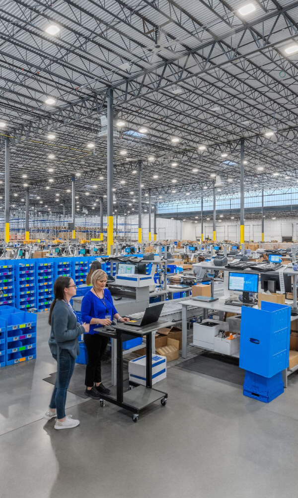 LED high bay lighting provides broad illumination across a warehouse distribution center with high ceilings and active fulfillment operations.