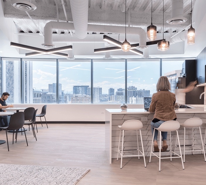 Modern X-shaped LED pendant lights offer low-glare accent lighting in a WeWork kitchen breakroom.