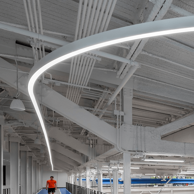 RGBW linear pendant lighting illuminates bowling alley lanes in vibrant blue, creating a cool atmosphere in a modern space.