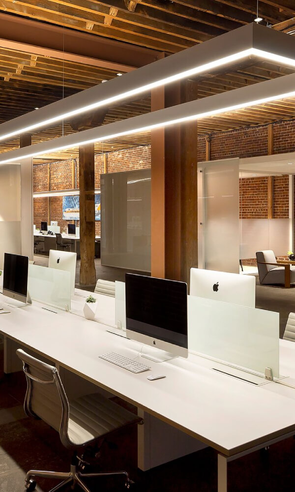 A long custom size rectangular pendant lights a shared workstation.