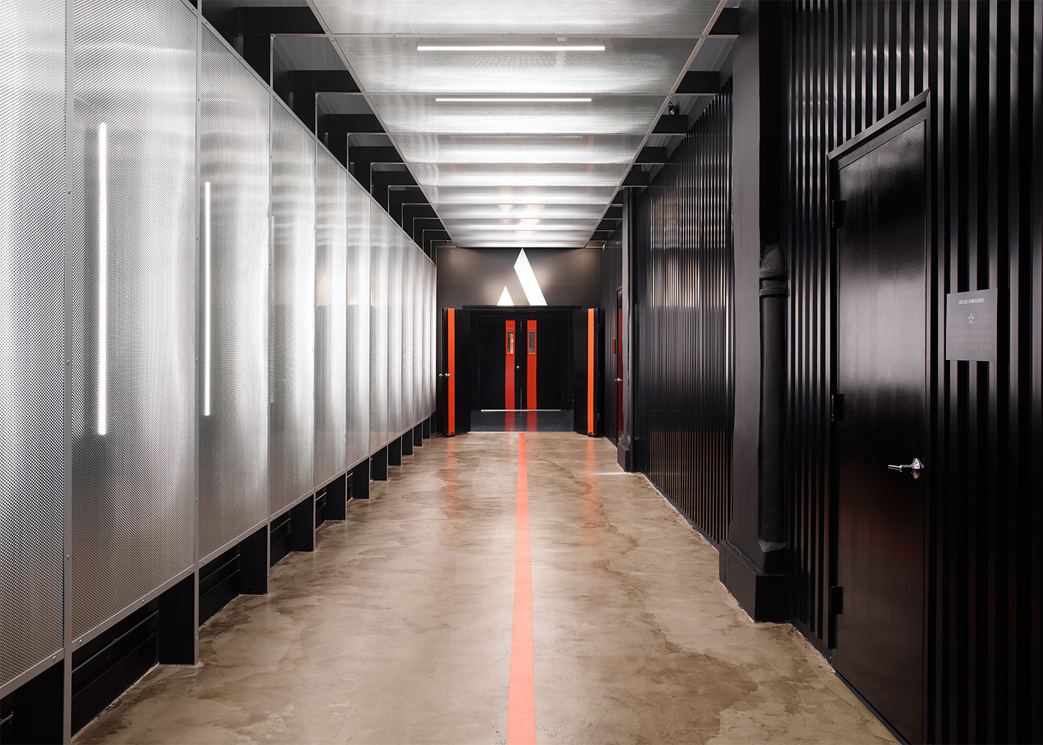 Linear ceiling and wall lights line the Hall of Champions at AARMY pop-up fitness studio, invigorating patrons as they enter the fitness area.