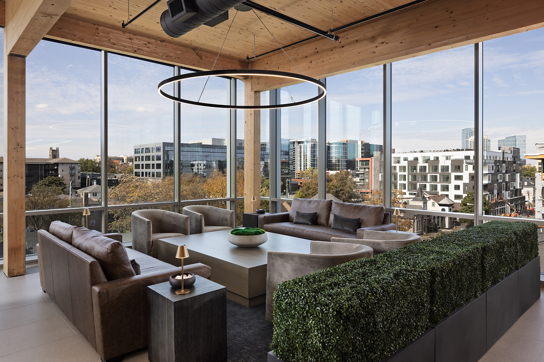An 8-foot slim LED ring pendant light hangs over a luxury breakroom area overlooking downtown Nashville in the Elmington Property Management headquarters.