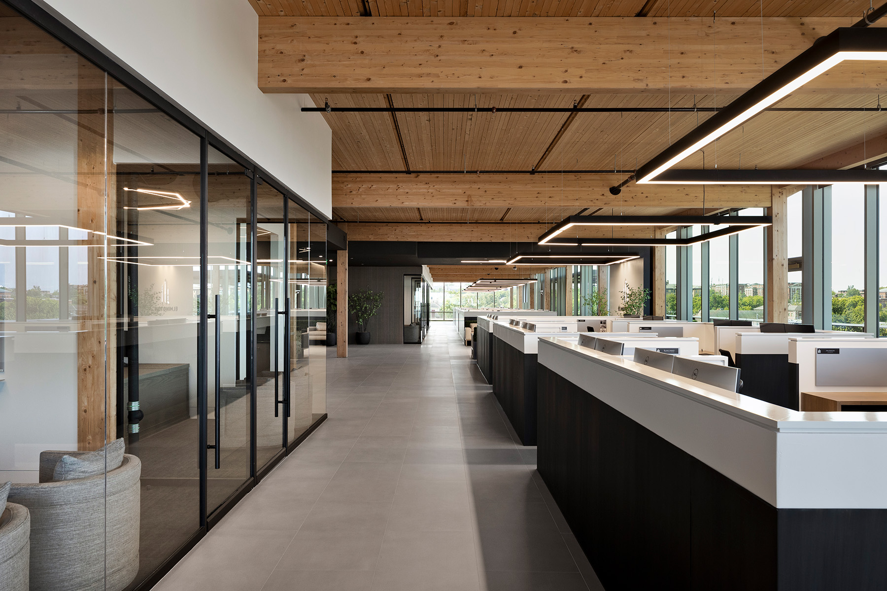 Oversized rectangular pendant LED lights help define team spaces with four workstations positioned within half-walls under each large fixture.