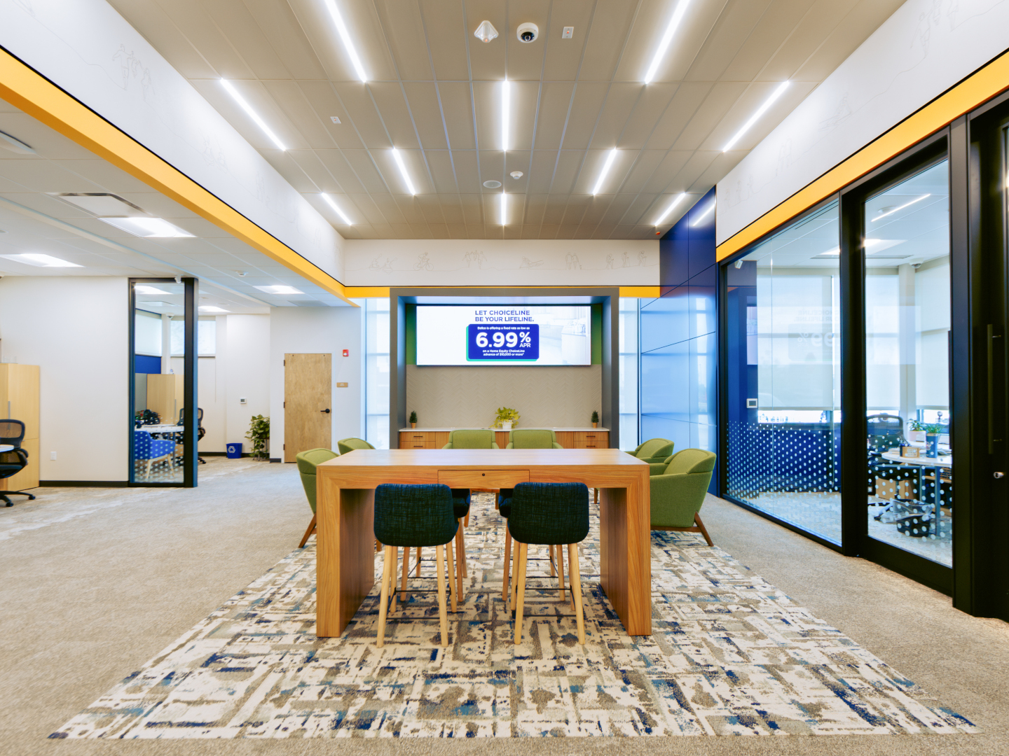 Integrated T-bar LED lights fit into a ceiling grid create a linear pattern over a conference and waiting area.