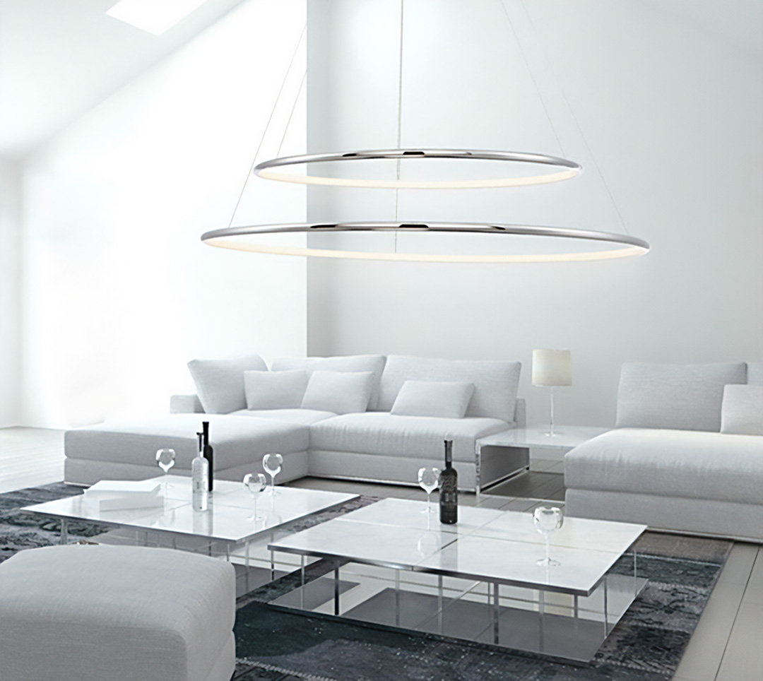 A two-tier silver ring chandelier hangs from a sloped ceiling over a modern living room
