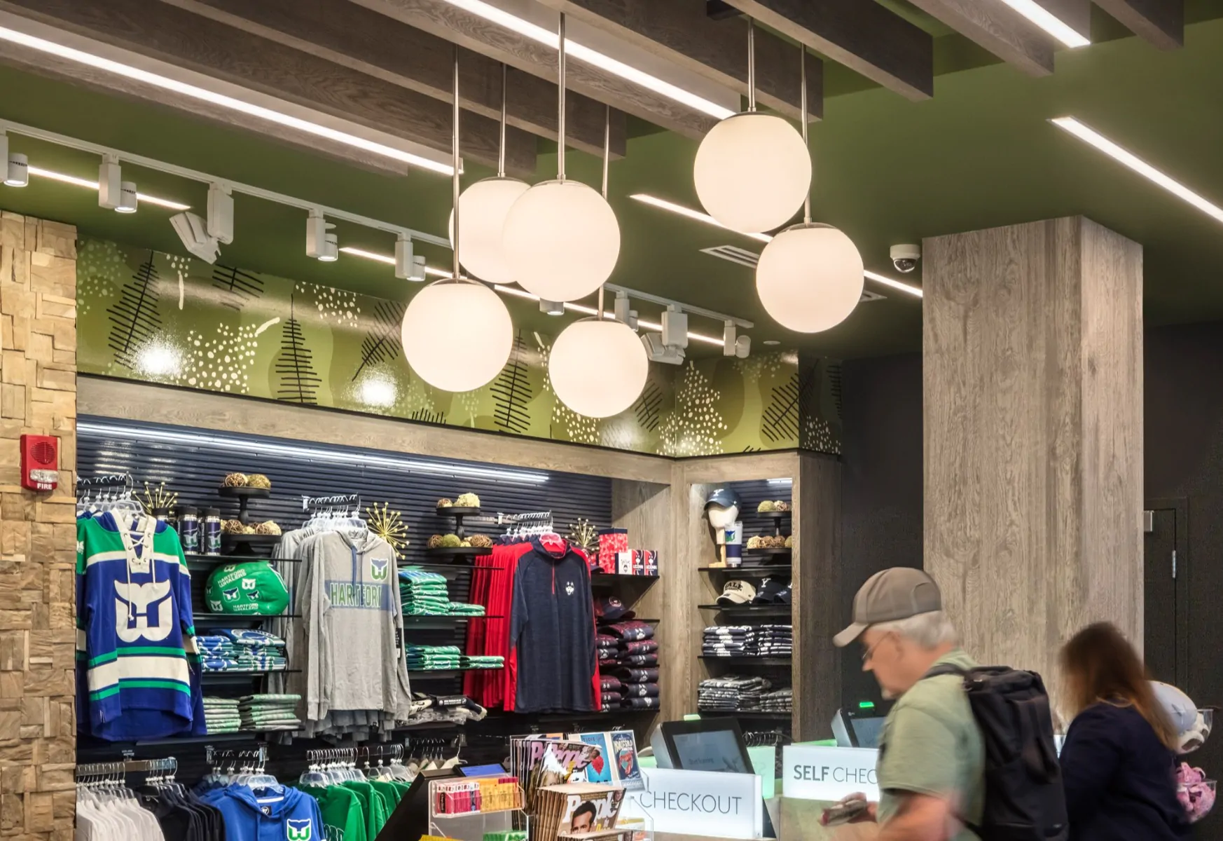 Modern LED globe pendant lights provide task lighting over an airport retail convenience store checkout.