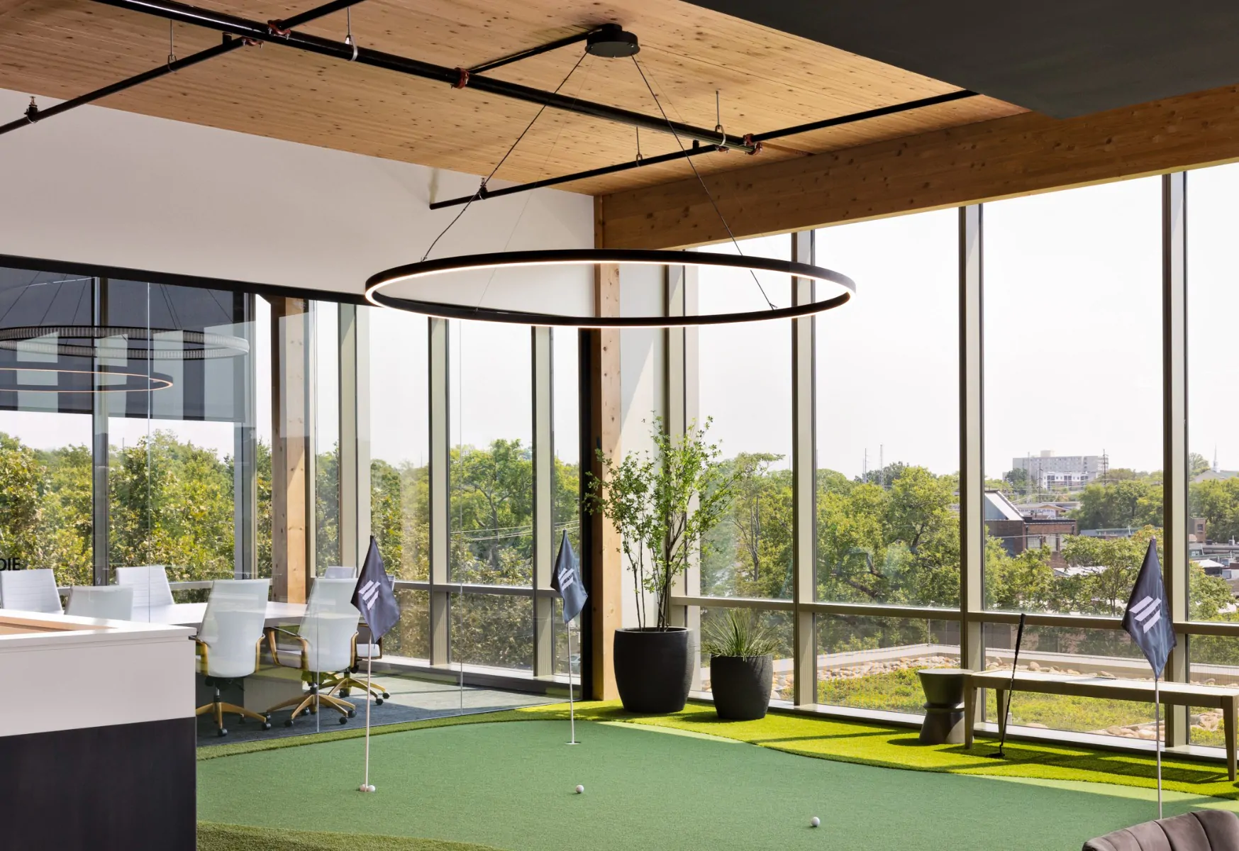 A slim ring pendant light provides soft, uniform illumination over an office putting green at Elmington's Nashville office.