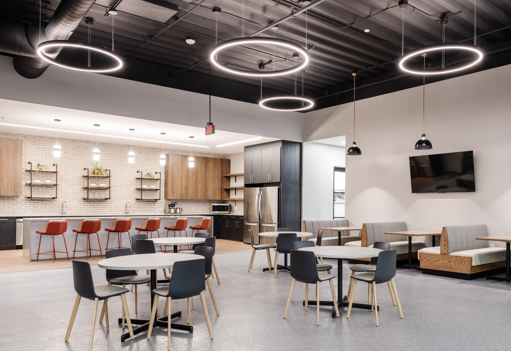 White round panel pendant lights suspended from a sloped ceiling on a white stem mounting, providing the customer clarity in wayfinding from the grocery store entrance. 