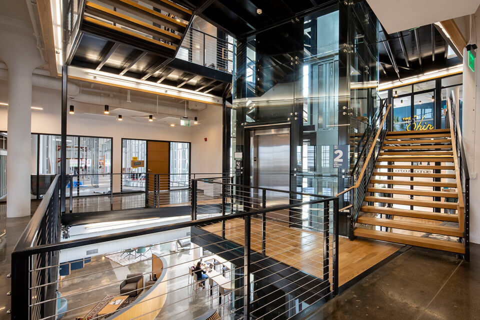 Two types of LED suspended light fixtures—cylinder downlights and linear suspension lights—light the Plant Seven offices in North Carolina