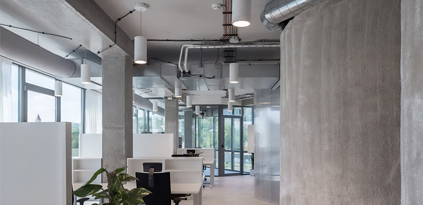 LED cylinder pendant lights hang over desks in a modern office