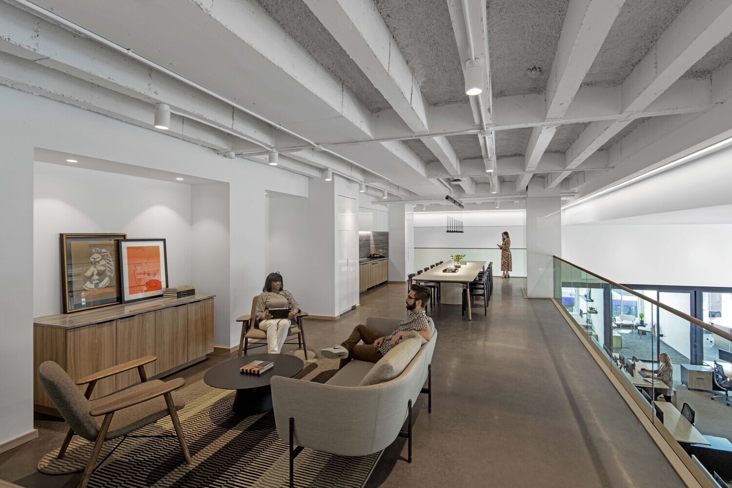 Surface-mounted white cylinder ceiling lights illuminate an office break area where staff can read and relax