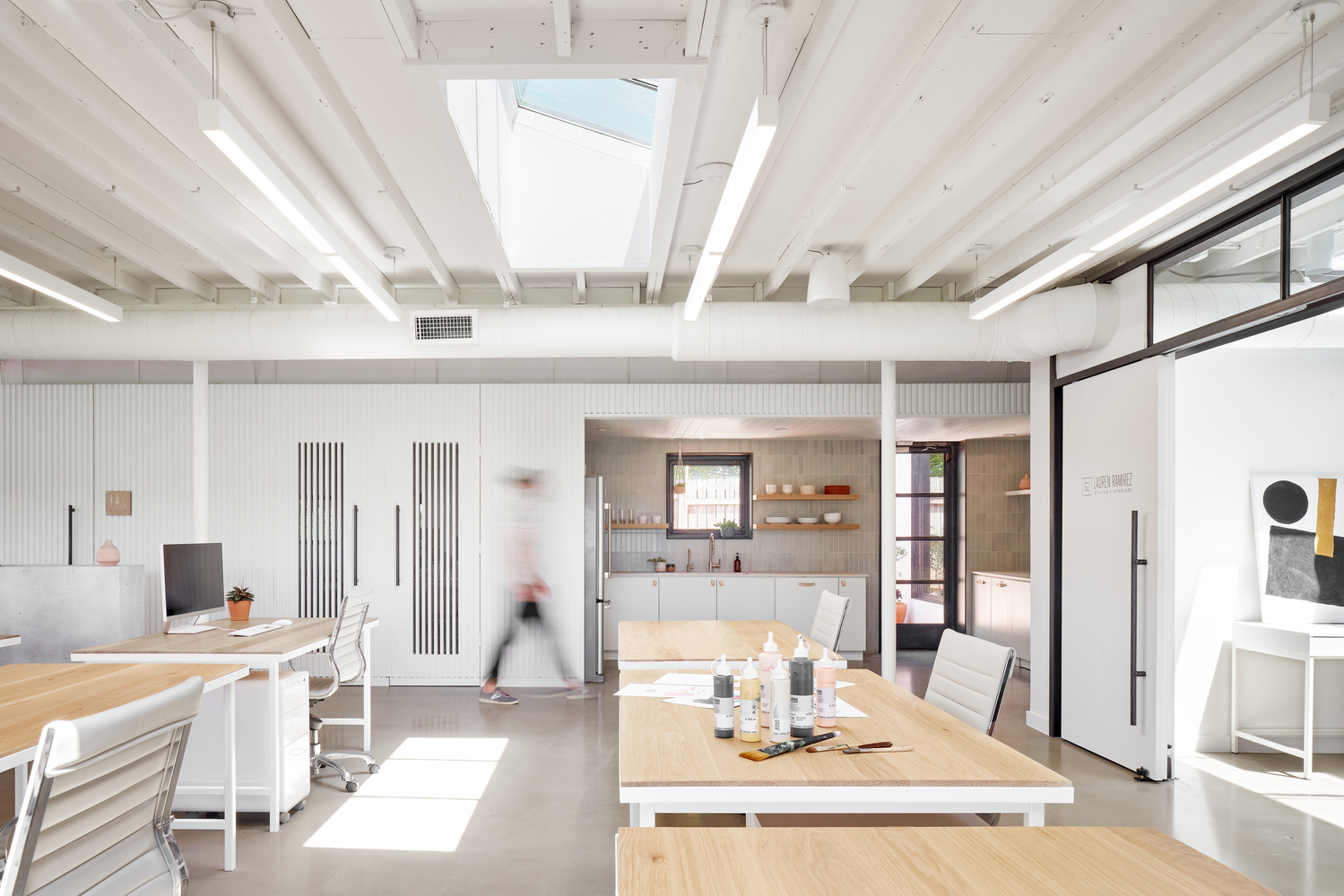 Black cylinder pendant lights with drop lenses provide ambient lighting in corridors of an old textile mill remade as a modern office.