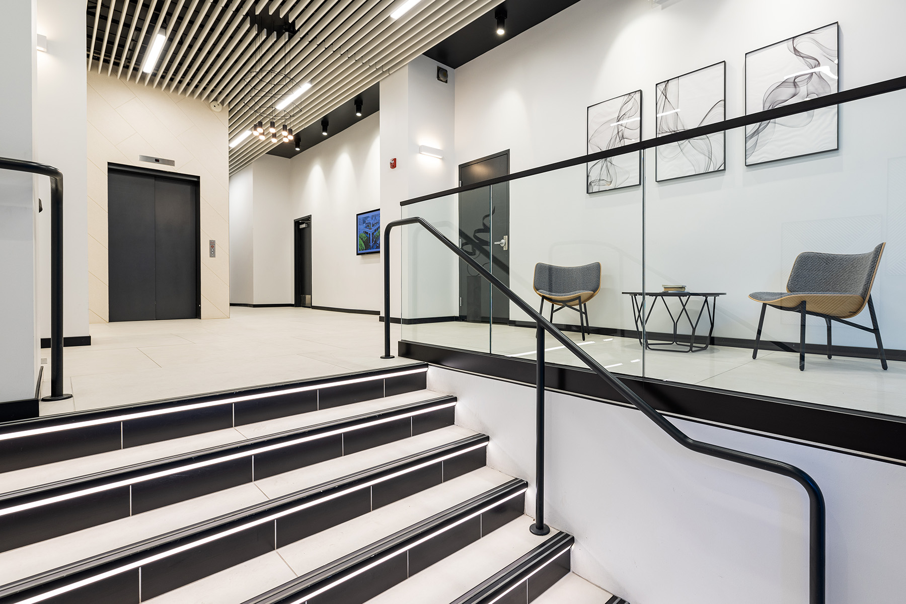 Linear pendant and wall lights, along with cylinder pendant lights, create a bright, welcoming atmosphere in the elevator lobby space of 735 Montgomery Street