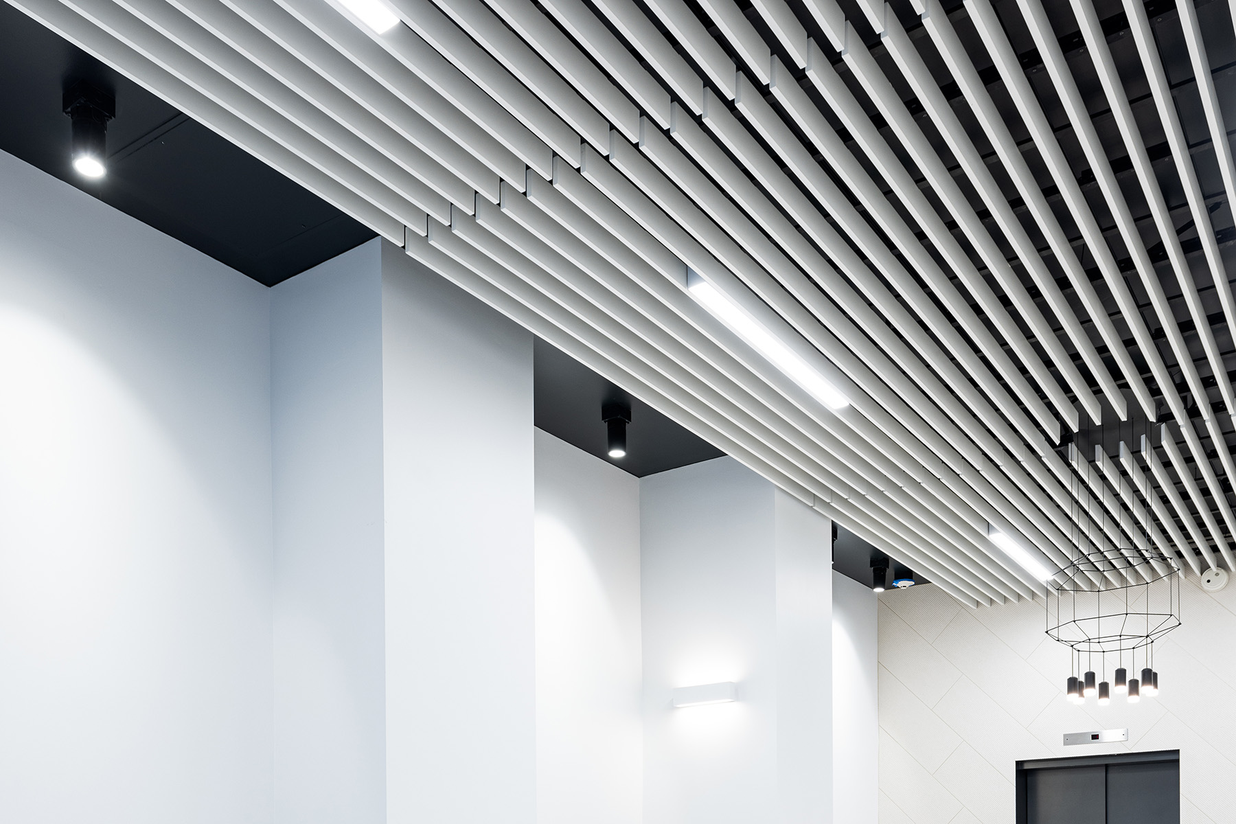 Closeup of the office light fixtures in the 735 Montgomery Street lobby, which include cylinder downlights, pendant lighting, linear lights, and wall-mounted up and down lights