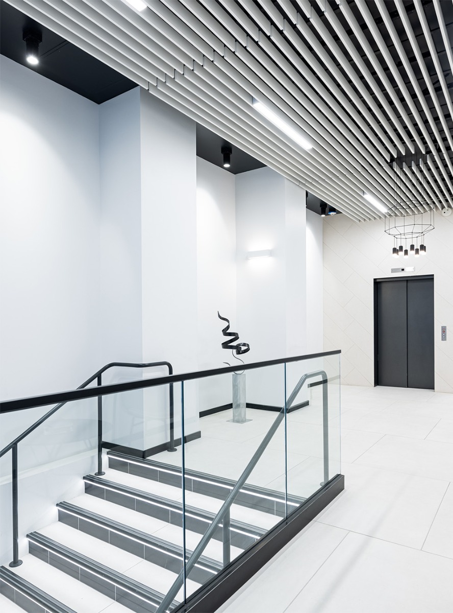 A combination of linear ceiling lights, cylinder downlights and indirect stair treading lighting illuminates the office lobby stairway at 735 Montgomery Street